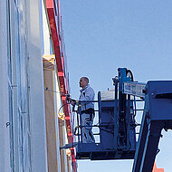 Rationelles Beschichten einer Metallfassade mit Airless-Gerät und Hubsteiger