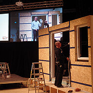»Schnittstelle Baustelle fokus«: Wand und Dach entstanden in der Halle auf der Bühne live